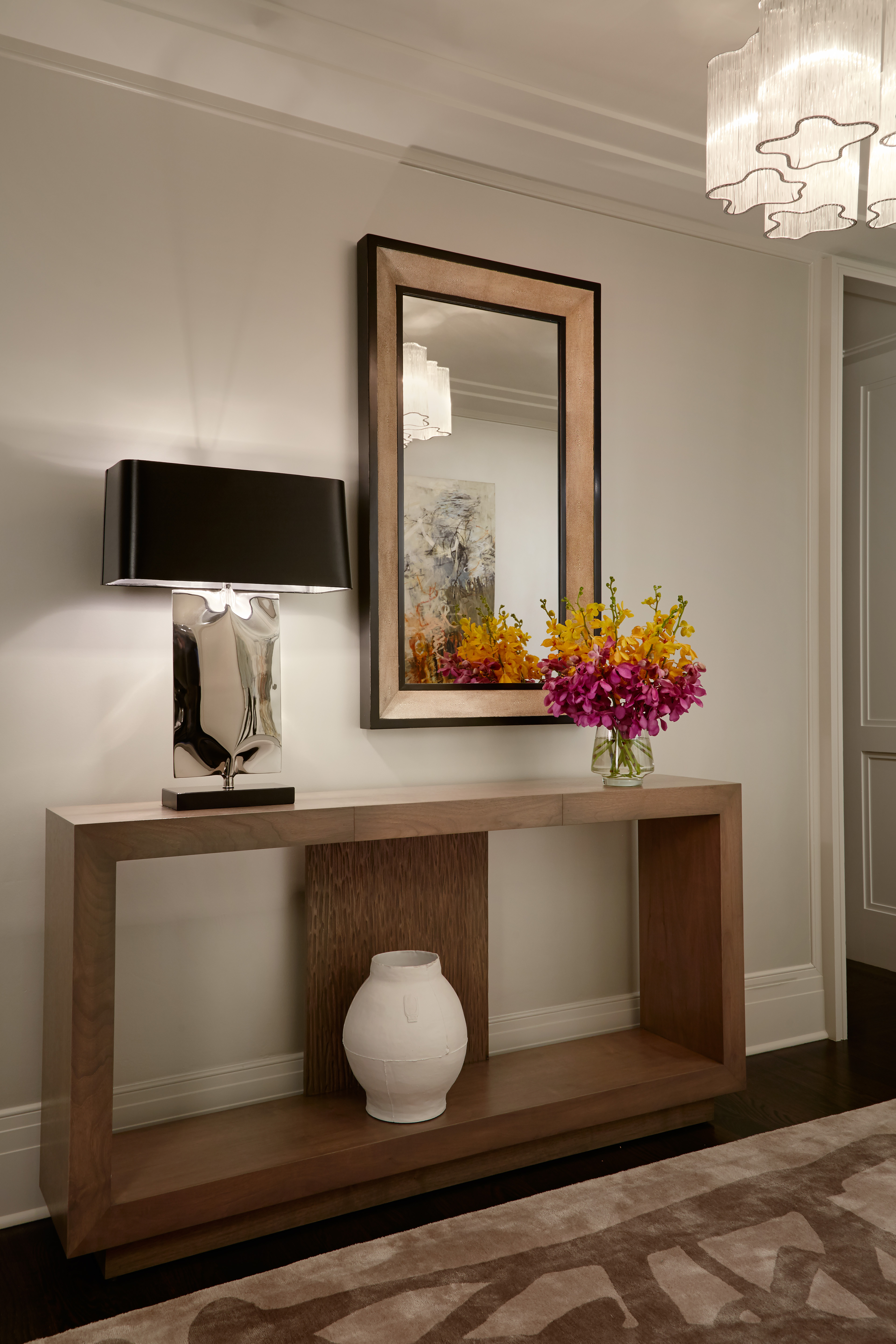 Bright and Airy Foyer incorporates mirrored table lamp, wooden open console table, and black and wooden mirror.