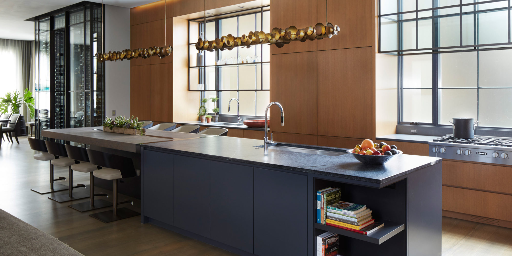 Kitchen design uses wood and dark tones, incorporating Ochre Chandeliers, and Usona Home Barstools.