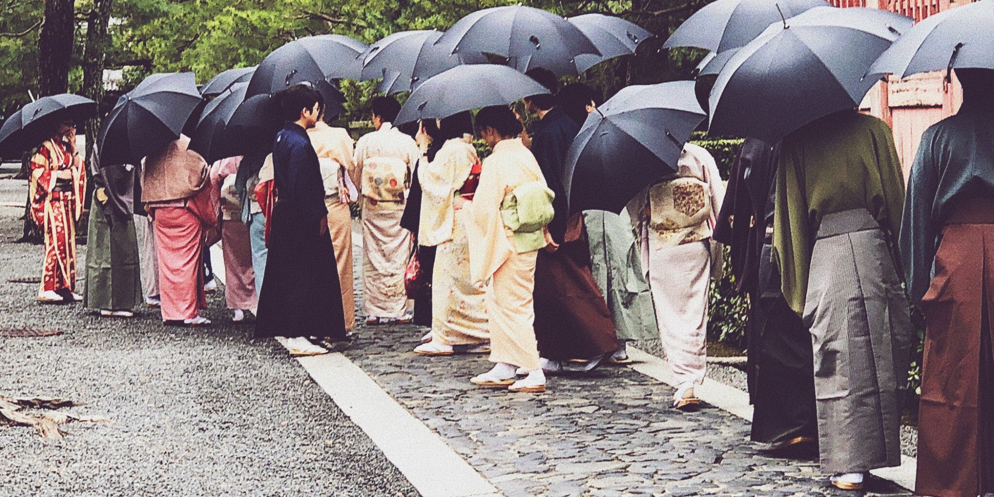 Street filled with geishas with umbrellas