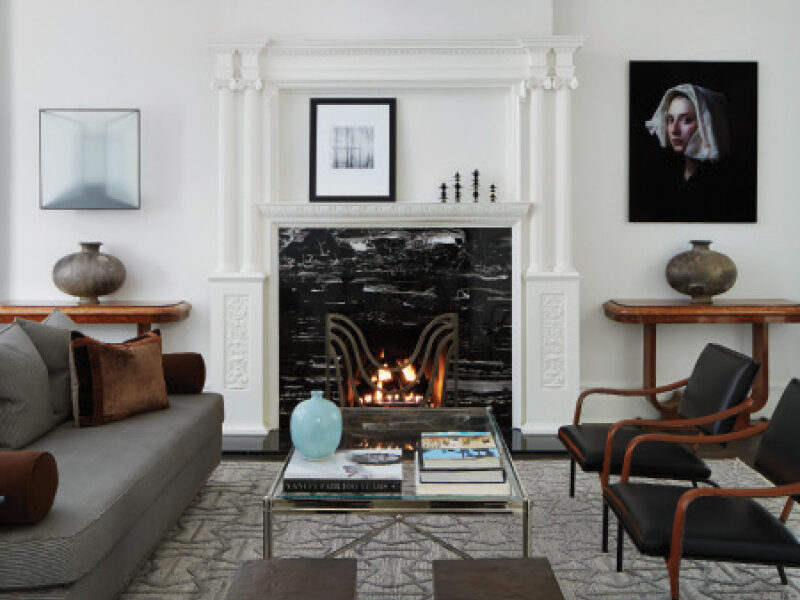 Living Room incorporates black marble fireplace, SHIIR Rug, antique chrome and glass coffee table, and wooden console tables.