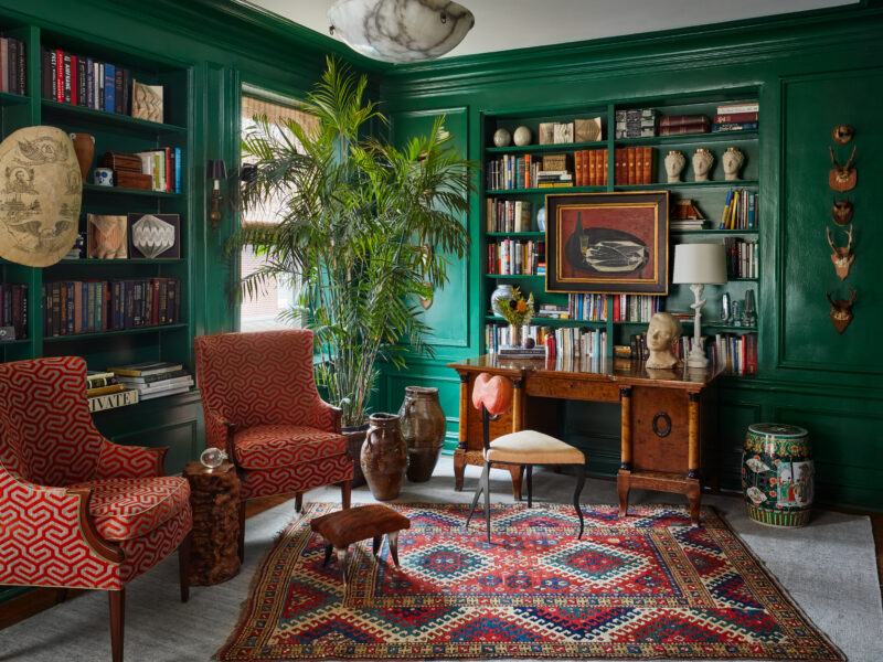 A SHIIR rug layered with a bold antique rug adds comfort and depth to vibrant earth tone office