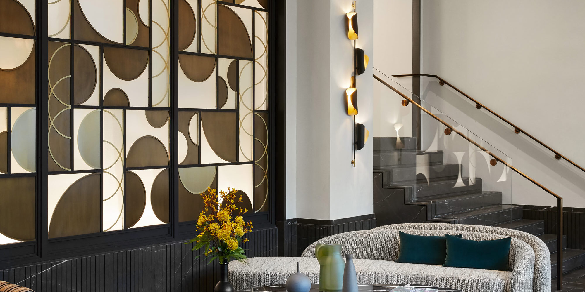 Apartment Waiting Area incorporating Black Marble Coffee Table, Striped Holly Hunt Lounge Chairs, Blue and Gold SHIIR Rug, and Glass Wall Paneling