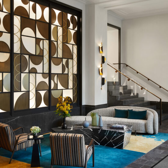 Apartment Waiting Area incorporating Black Marble Coffee Table, Striped Holly Hunt Lounge Chairs, Blue and Gold SHIIR Rug, and Glass Wall Paneling