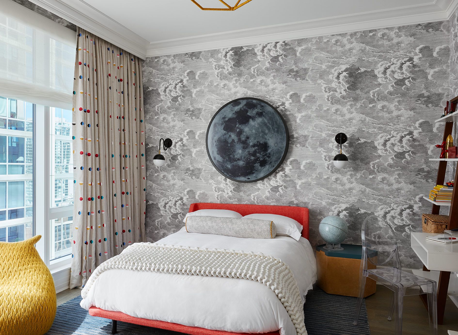 Boys Bedroom incorporating grey clouds wallcovering, red upholstered bed, moon light above bed.