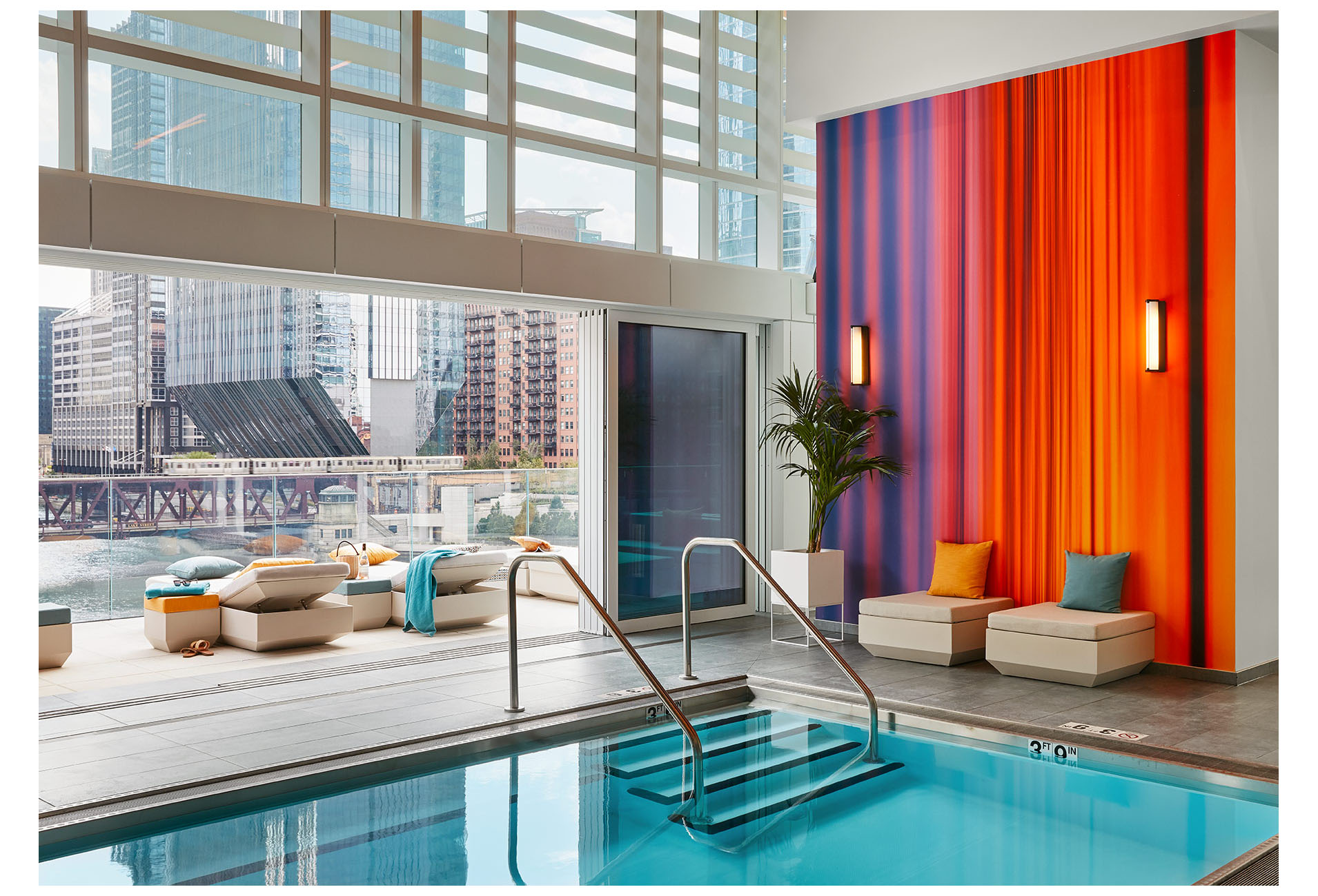 Indoor Pool Connected to the Outdoor Patio with Colorful Wall Covering and Colorful Lounge Chairs